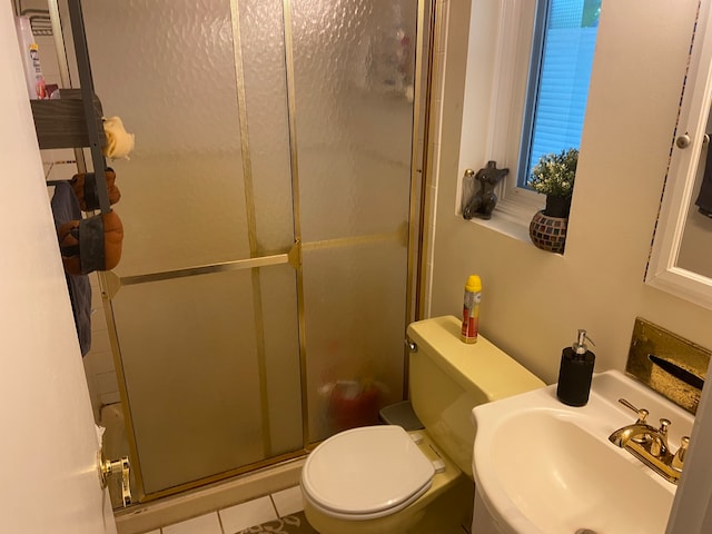 bathroom with toilet, tile patterned flooring, sink, and a shower with door