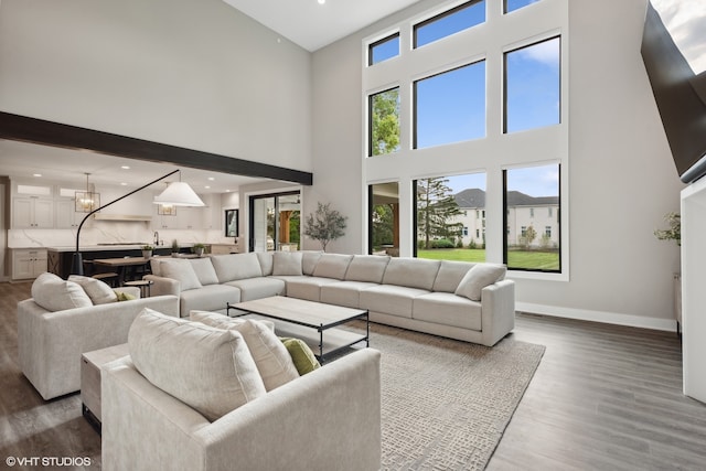 living room featuring a high ceiling, a chandelier, and hardwood / wood-style floors