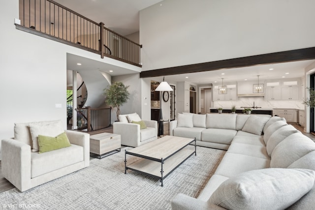 living room featuring an inviting chandelier, a towering ceiling, and beam ceiling