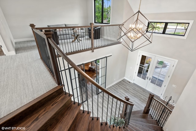 staircase with wood-type flooring, french doors, and a notable chandelier