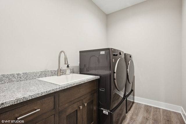 laundry area with light wood-type flooring, sink, washing machine and clothes dryer, and cabinets