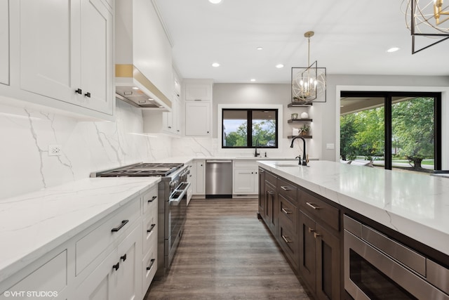 kitchen featuring custom exhaust hood, stainless steel appliances, plenty of natural light, and a notable chandelier