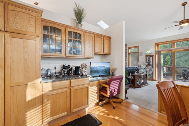 office area featuring light wood-type flooring, lofted ceiling, built in desk, and ceiling fan