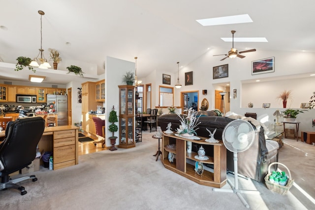 living room featuring high vaulted ceiling, light colored carpet, a skylight, and ceiling fan with notable chandelier