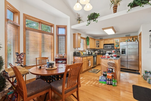 dining space featuring light wood-type flooring, sink, and vaulted ceiling