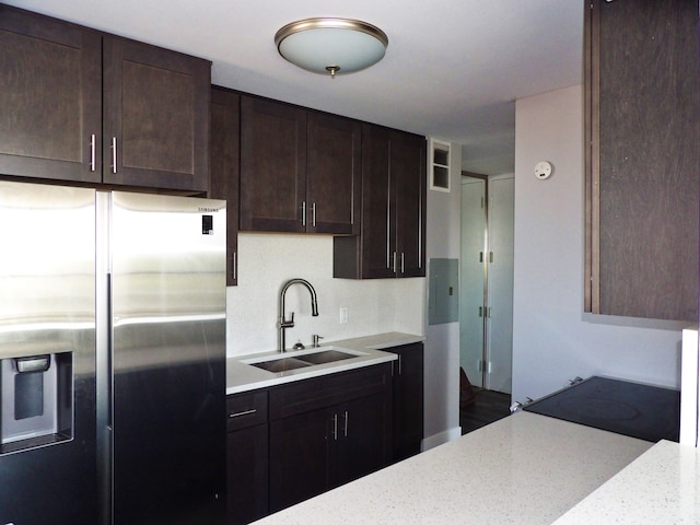 kitchen featuring dark brown cabinetry, sink, light stone counters, range, and stainless steel fridge