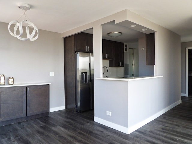 kitchen featuring dark brown cabinets, kitchen peninsula, dark hardwood / wood-style floors, and stainless steel fridge