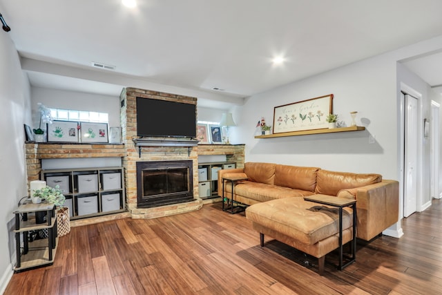 living room featuring a brick fireplace and hardwood / wood-style flooring