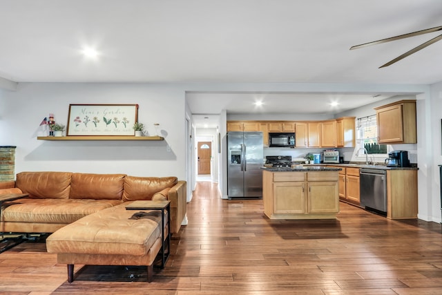 kitchen with black appliances, light brown cabinetry, a center island, ceiling fan, and hardwood / wood-style flooring