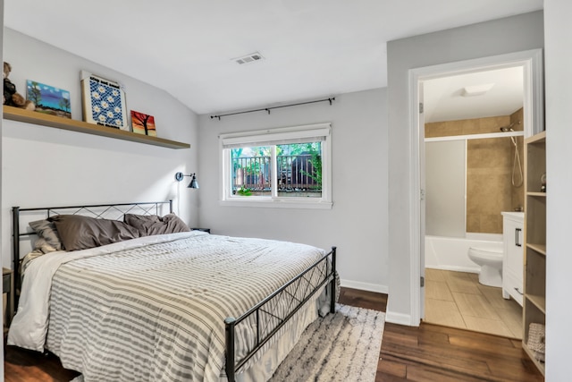 bedroom with connected bathroom and dark hardwood / wood-style floors