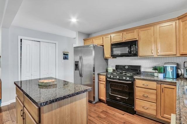 kitchen featuring dark stone countertops, backsplash, a center island, light hardwood / wood-style floors, and black appliances