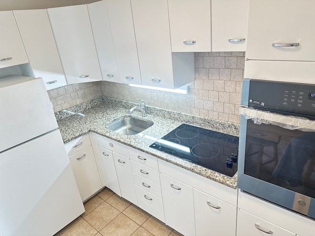 kitchen with white refrigerator, oven, white cabinetry, and sink