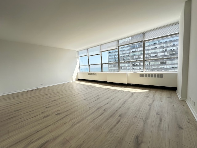 spare room with radiator heating unit and light hardwood / wood-style floors