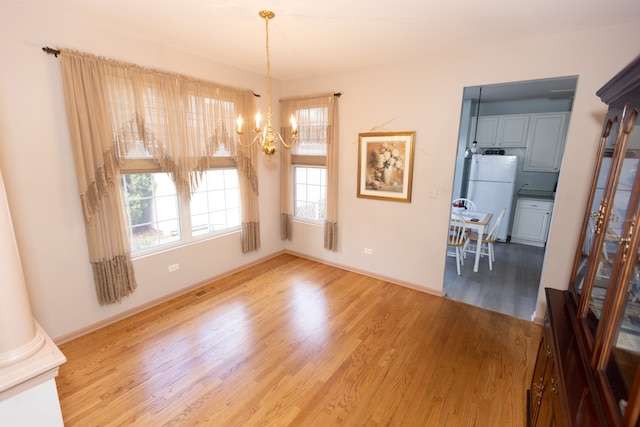 unfurnished dining area with ornate columns, hardwood / wood-style floors, and a chandelier