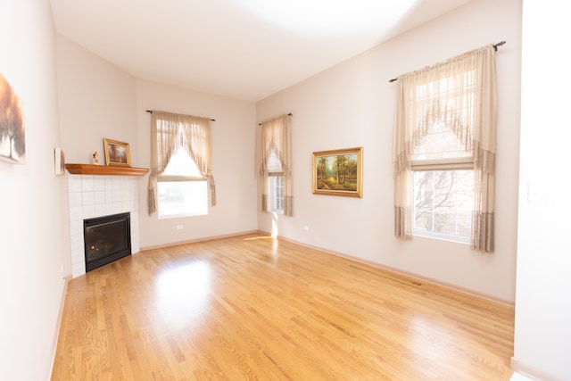 unfurnished living room with a fireplace, a wealth of natural light, and light hardwood / wood-style flooring