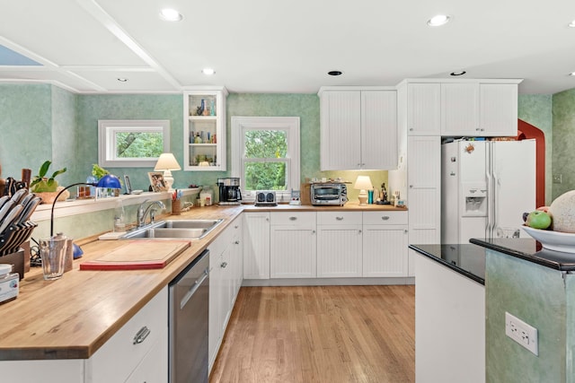 kitchen featuring butcher block counters, white fridge with ice dispenser, stainless steel dishwasher, and white cabinets