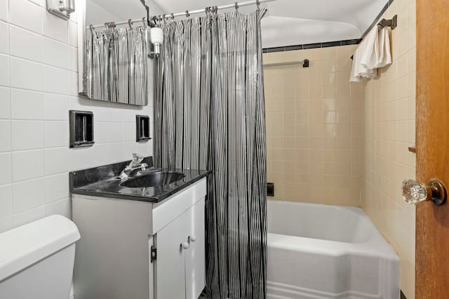 full bathroom with vanity, toilet, shower / bathtub combination with curtain, and tile walls