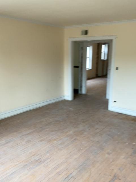 spare room featuring light wood-type flooring and crown molding