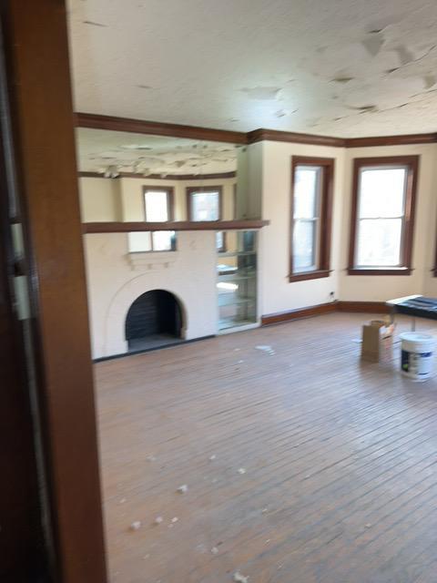 unfurnished living room featuring hardwood / wood-style floors and crown molding