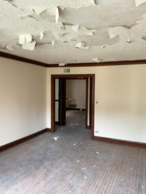 unfurnished room with crown molding, a textured ceiling, and hardwood / wood-style flooring