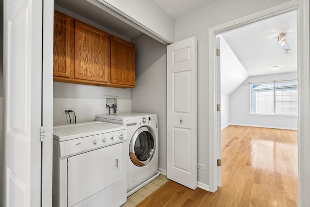 washroom with independent washer and dryer, cabinets, and light hardwood / wood-style flooring