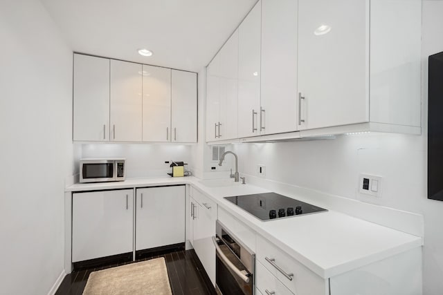 kitchen featuring dark wood-type flooring, sink, stainless steel appliances, and white cabinets