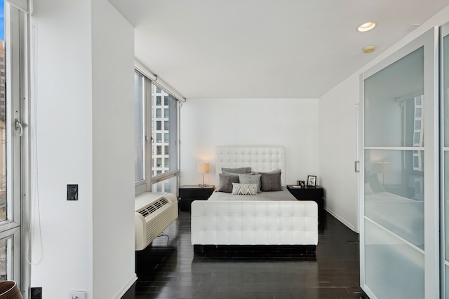 bedroom with a wall unit AC and dark hardwood / wood-style floors