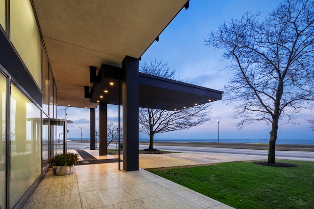 patio terrace at dusk with a yard and a water view