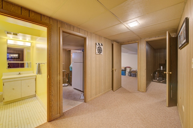 hallway featuring light colored carpet and wood walls