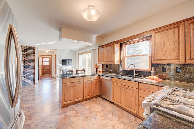 kitchen with sink, kitchen peninsula, decorative backsplash, stainless steel appliances, and light tile patterned floors