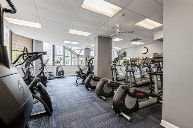 workout area with ceiling fan, a drop ceiling, and dark colored carpet