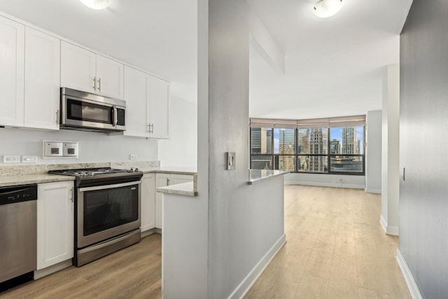 kitchen with light wood-type flooring, stainless steel appliances, and white cabinetry