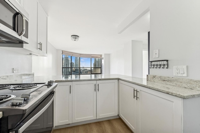 kitchen with white cabinets, kitchen peninsula, electric range, and light stone counters