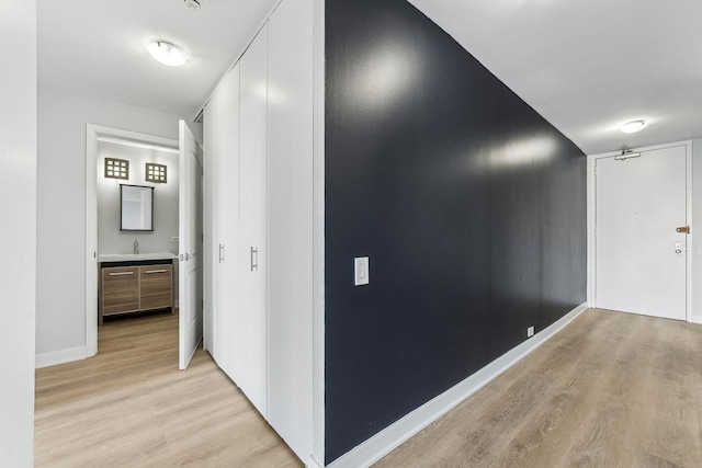 hallway with light hardwood / wood-style flooring and sink