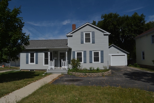 view of front of property featuring a front lawn, a garage, covered porch, and an outdoor structure