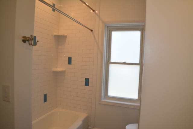 bathroom featuring toilet and tiled shower / bath combo