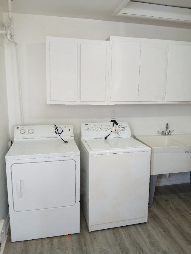 laundry area featuring sink, independent washer and dryer, wood-type flooring, and cabinets