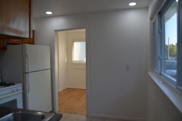 kitchen featuring a healthy amount of sunlight, light tile patterned flooring, and white refrigerator