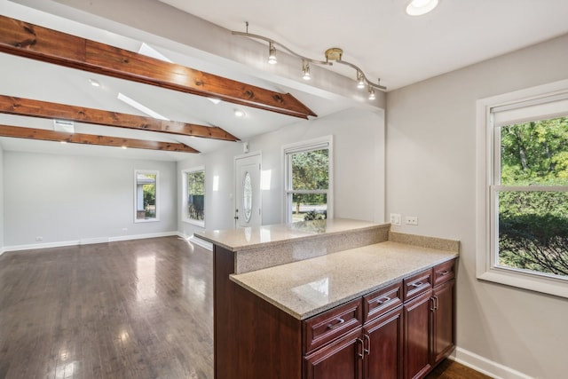 kitchen featuring dark wood-type flooring, lofted ceiling with beams, a wealth of natural light, and kitchen peninsula