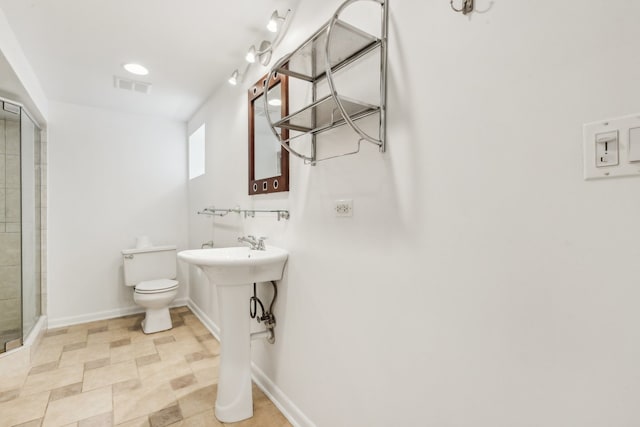 bathroom featuring a shower with door and toilet