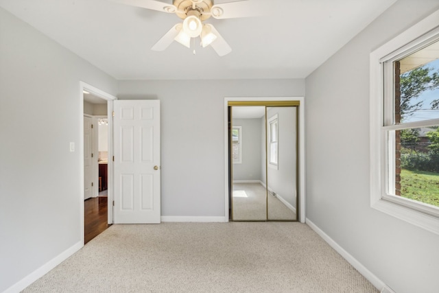 unfurnished bedroom with multiple windows, a closet, carpet, and ceiling fan