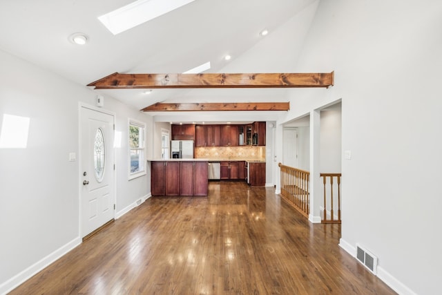 kitchen with lofted ceiling with skylight, decorative backsplash, stainless steel appliances, and dark hardwood / wood-style floors