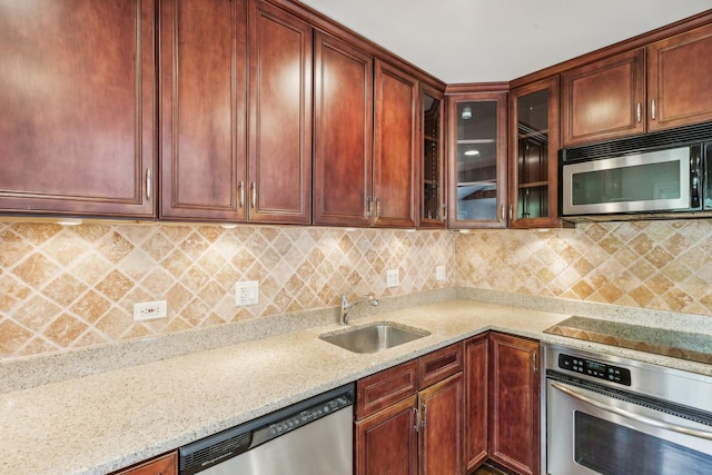 kitchen with stainless steel appliances, sink, light stone counters, and backsplash