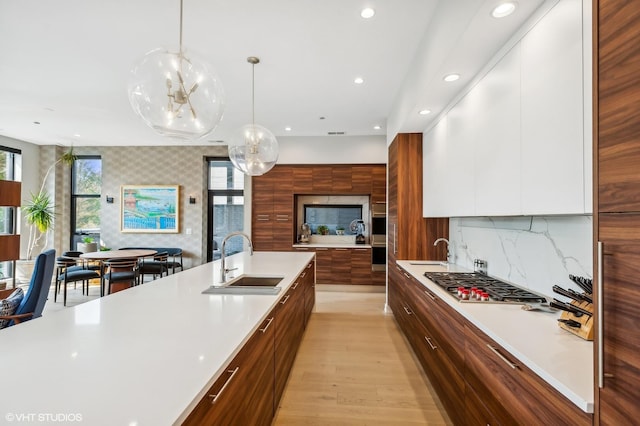 kitchen featuring modern cabinets, a sink, stainless steel gas cooktop, light countertops, and recessed lighting