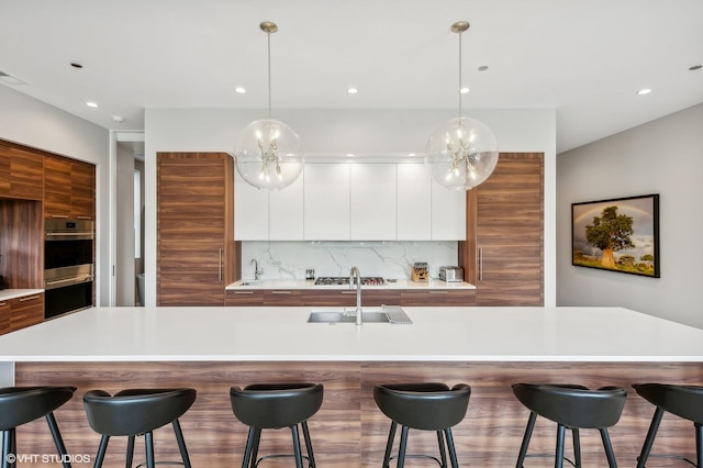 kitchen with modern cabinets, a sink, backsplash, stainless steel appliances, and recessed lighting