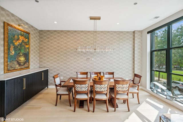 dining area featuring wallpapered walls, baseboards, and light wood-type flooring