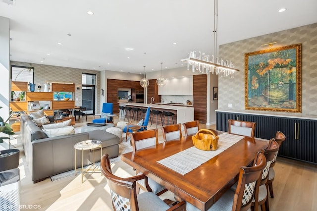dining area featuring wallpapered walls, light wood finished floors, recessed lighting, and an accent wall