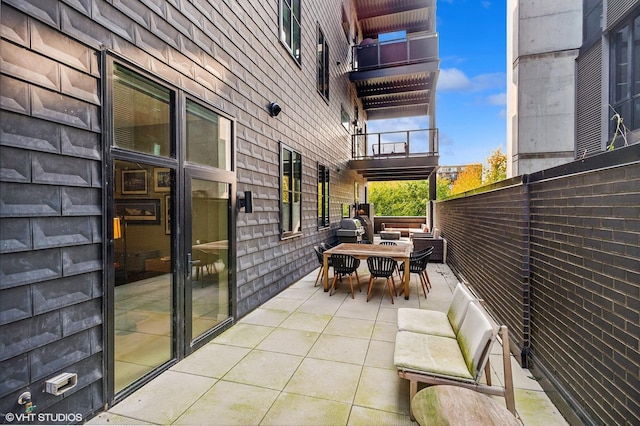 view of patio / terrace featuring outdoor dining space, a balcony, and fence