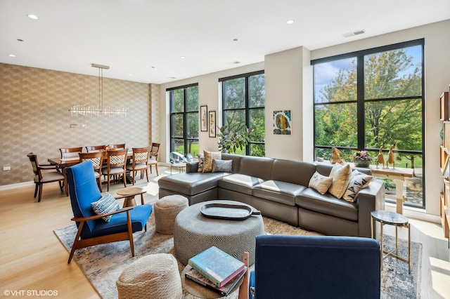 living area featuring wallpapered walls, light wood-style floors, baseboards, recessed lighting, and an accent wall