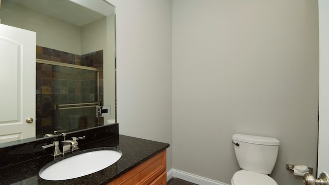 bathroom featuring a shower with door, vanity, and toilet